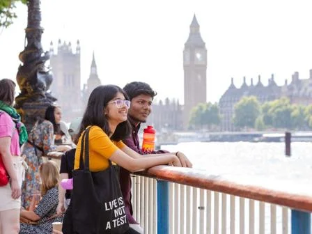 Two students look across the river Thames with Big Ben in the background