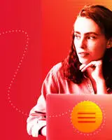 A woman with long hair looks thoughtfully to the side, seated at a laptop.