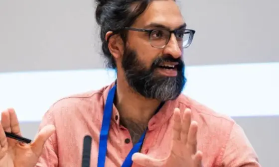 Man wearing lanyard gesturing while speaking