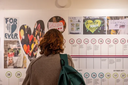 A photo of a woman looking at a Grenfell Tower exhibition