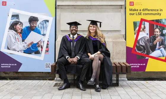 Two graduates sitting on a bench on LSE campus