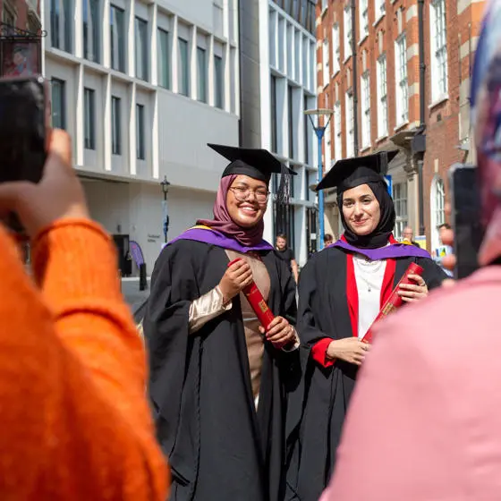 Two graduates posing for a photo with their diploma