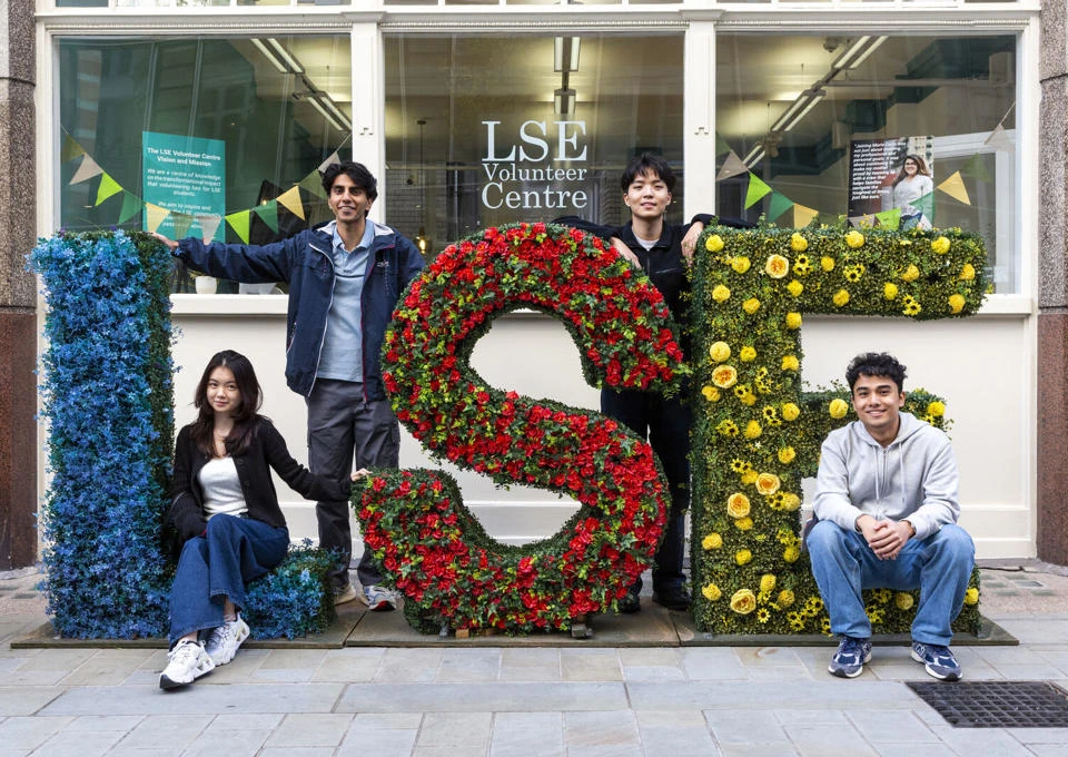 LSE students standing by LSE flower arrangements on campus