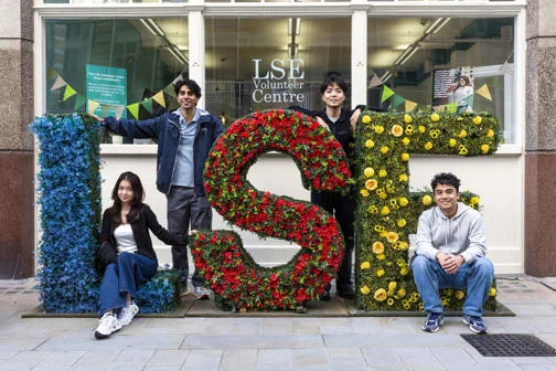 LSE students standing by LSE flower arrangements on campus