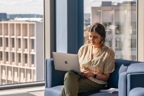 A propective student looking at a laptop with LSE campus in the background