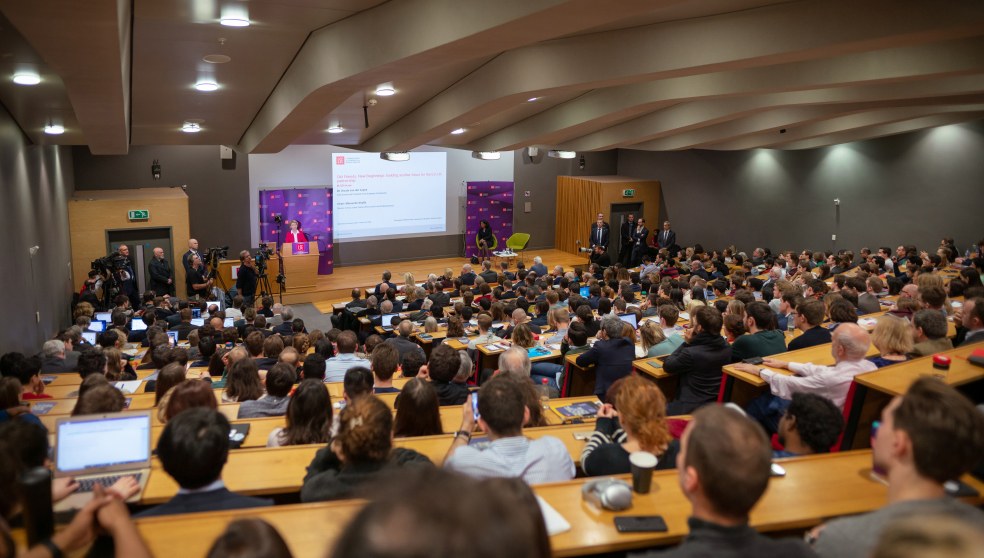 a photo of a lecture hall filled with students, from the back of the room