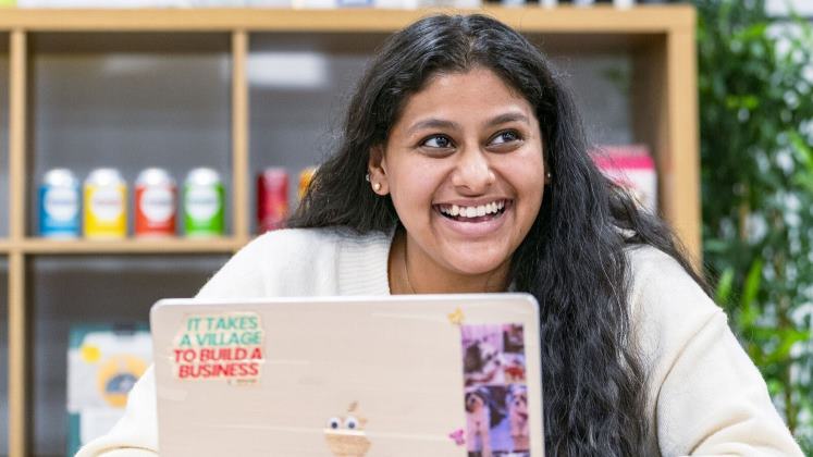 A smiling student using a laptop