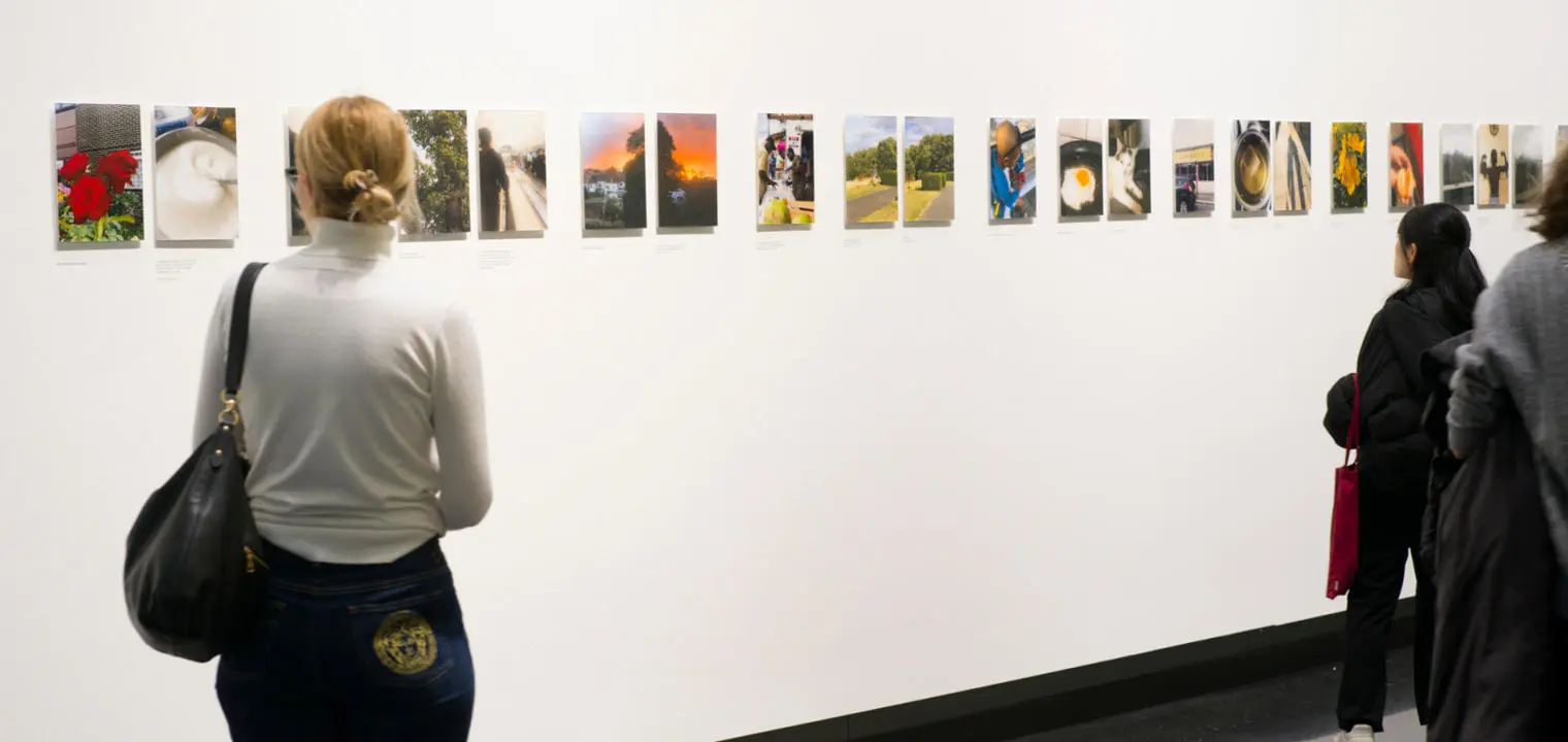 People looking at exhibition of photographs about life during a cost of living crisis