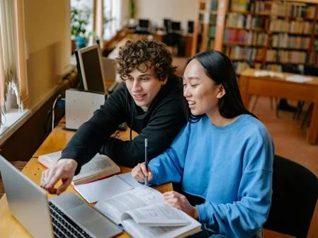 two students studying together around laptop