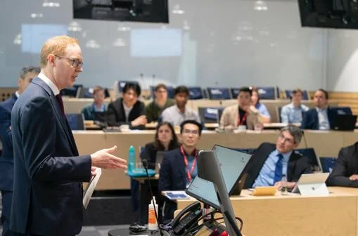 A man in a suit speaks to a lecture theatre.