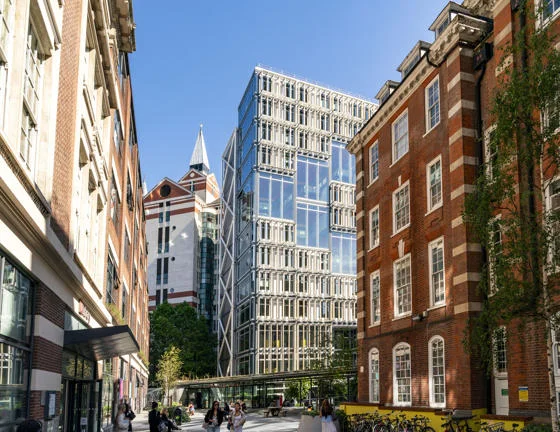 LSE Library plaza, facing the Centre Building on a sunny day. Students walking across plaza.