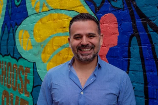 Headshot of Carlos Miranda in front of a colourful wall
