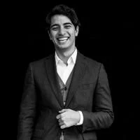 Daniel is laughing and wearing a suit. The photo is black and white,