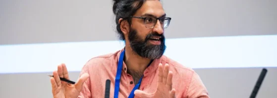 Man wearing lanyard gesturing while speaking