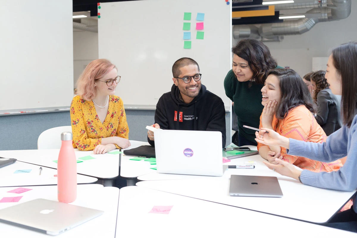 Students looking at a laptop and smiling and talking