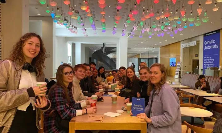 students sat on a long table drinking tea and coffe
