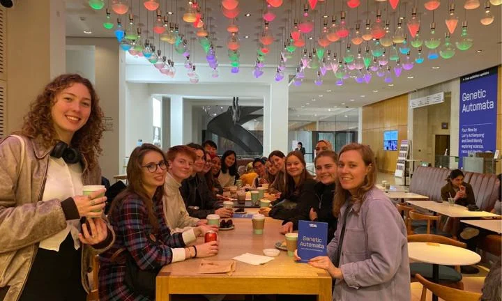students sat on a long table drinking tea and coffe