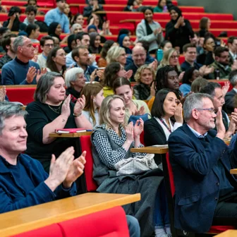 rows of people clapping, seated in a lecture theatre