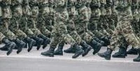 Soldiers dressed in army camouflage march in formation.