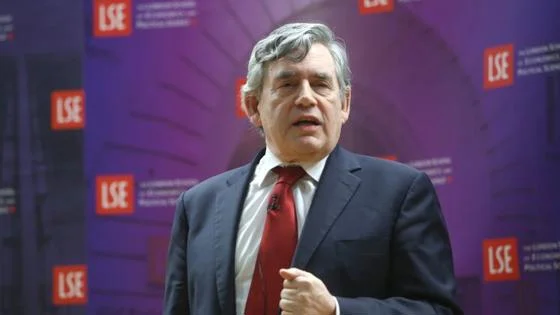 Gordon Brown speaking in front of an LSE banner.