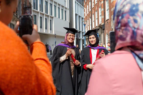 Two graduates posing for a photo with their diploma