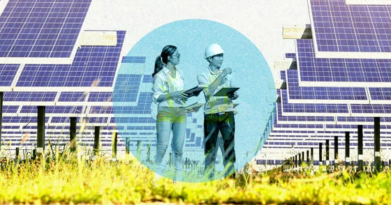 Two people with clipboards stand looking at a row of solar panels