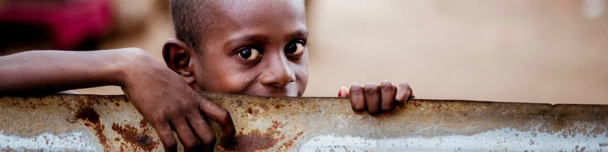 A boy gripping onto a rusty metal railing.