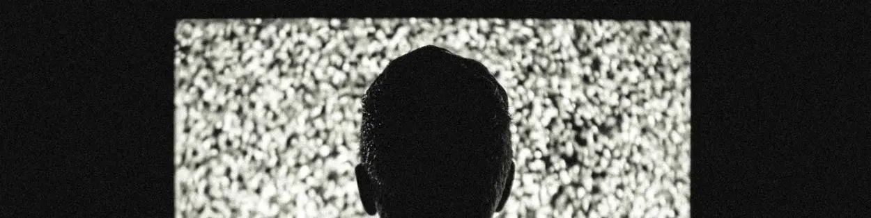 A man's head looking at a TV screen