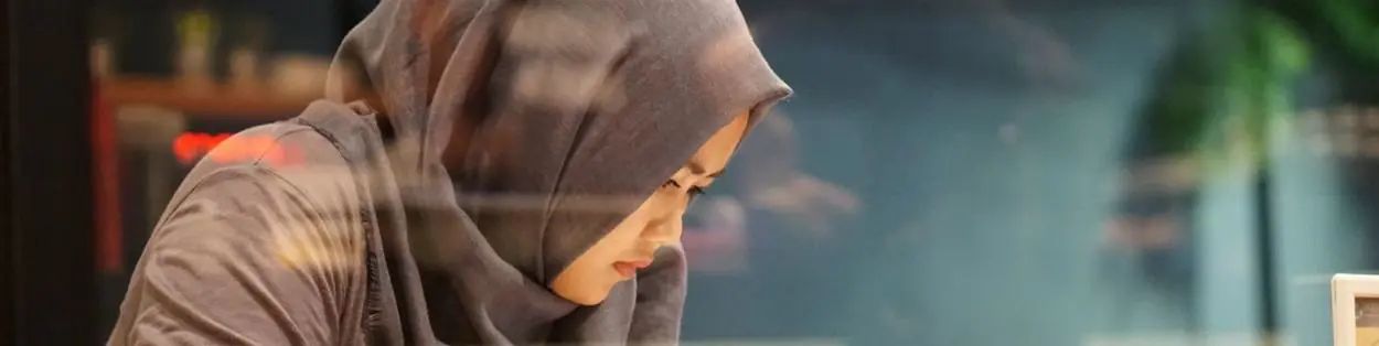 A girl weaing a headscarf looking down.