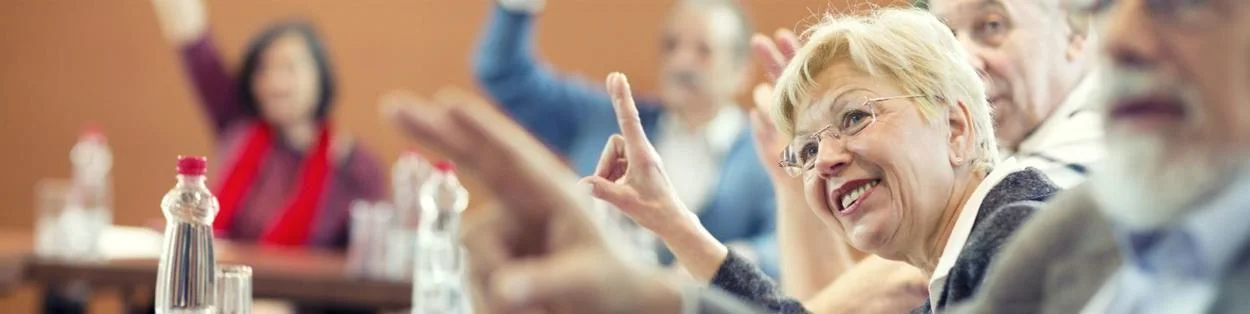 a room with elderly people raising their hands