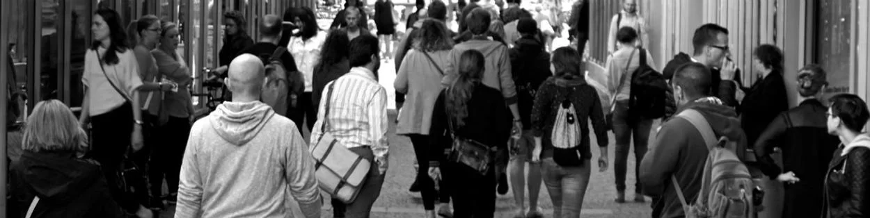 A black and white photo of people walking on a high street.