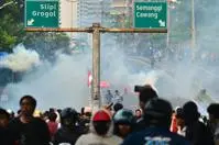 Crowd of protestors shrouded in smoke under highway signs