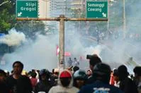 Crowd of protestors shrouded in smoke under highway signs