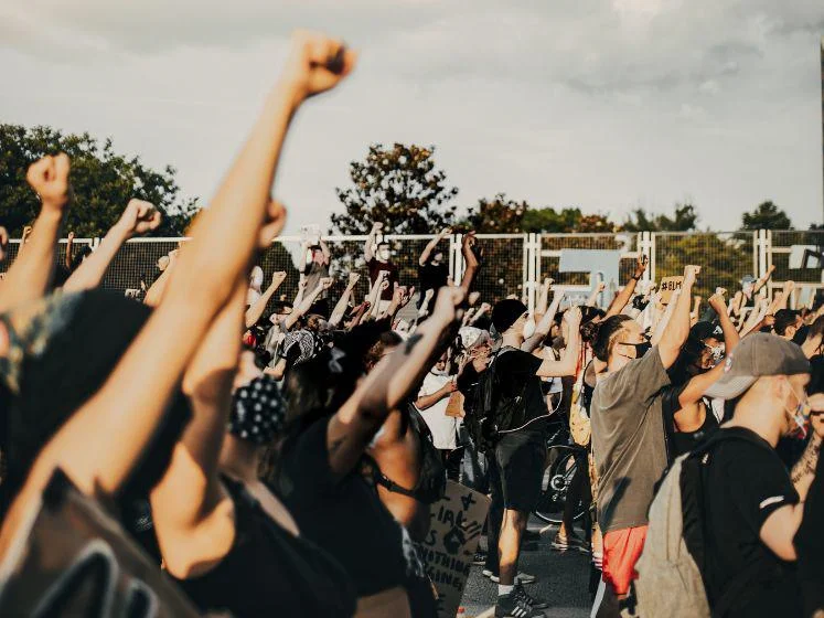 Protest scene with people holding placards and raising their fists.