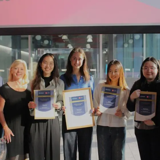 A group of four geography students posing with their certificates next to Chronos judges.
