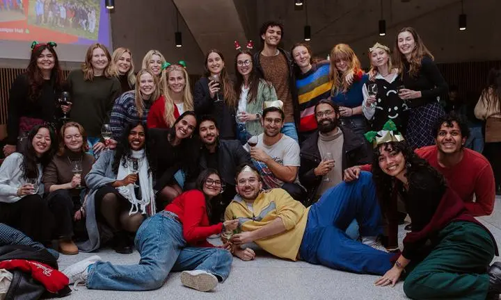 A group of master's students wearing festive headbands and smiling to camera.