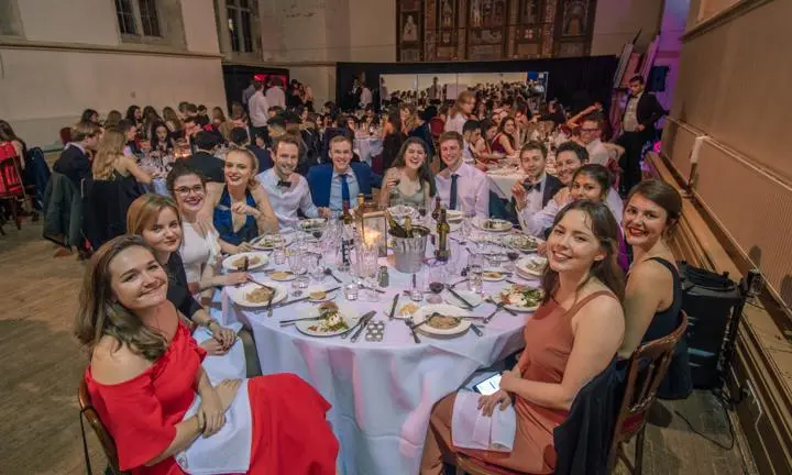 Students at the Winter Ball sitting at a round formal table with food and drink.