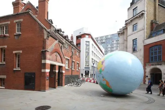 Picture of The World Turned Upside Down, an upside down colourful globe with an empty LSE campus in the background.