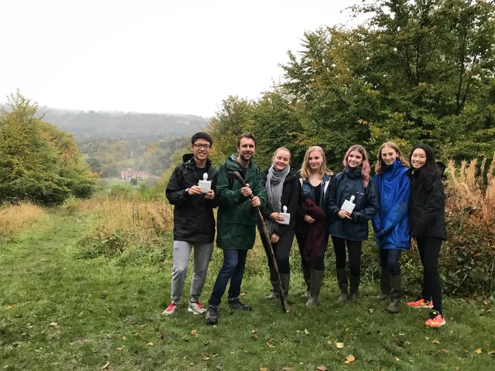 A group of students and staff posing with Juniper Hall in the background.