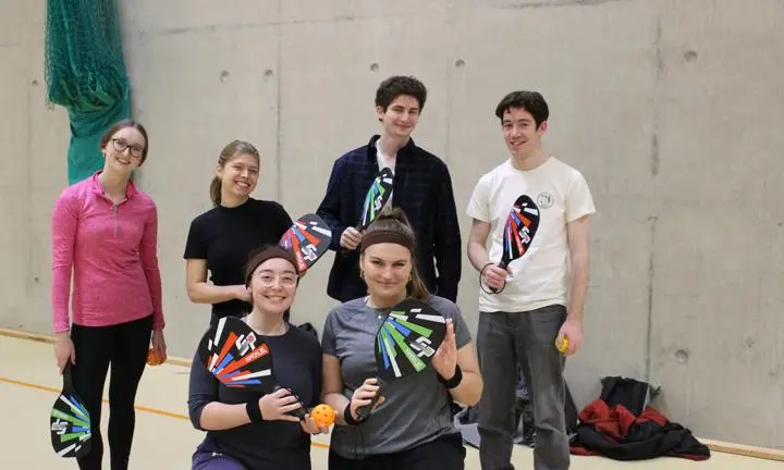 Students wearing activewear and holding paddles.