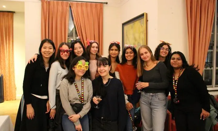A group of undergraduates wearing novelty glasses and smiling to camera.