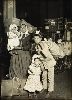 Italian family (mother and children) in the baggage room, Ellis Island, 1905