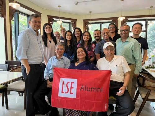 A group of alumni celebrating Global Networking Night in Kolkata, while proudly holding up the LSE alumni flag.