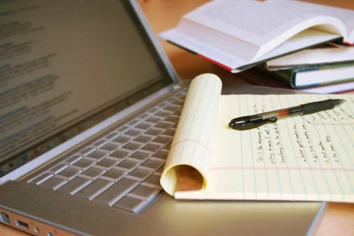 Photo of a laptop computer with handwritten notes beside it