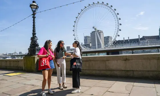 LSE students talking near the Thames with the London Eye in the background
