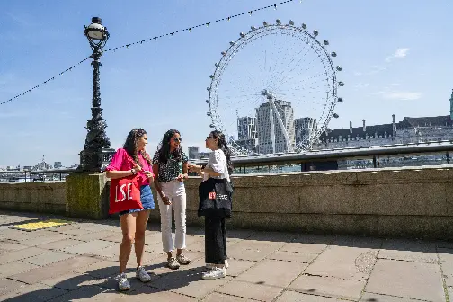 Three LSE students talking near the Thames with the London Eye in the background