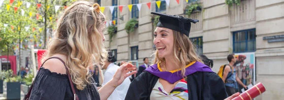 Two students talking to each other after their graduation ceremony at LSE.