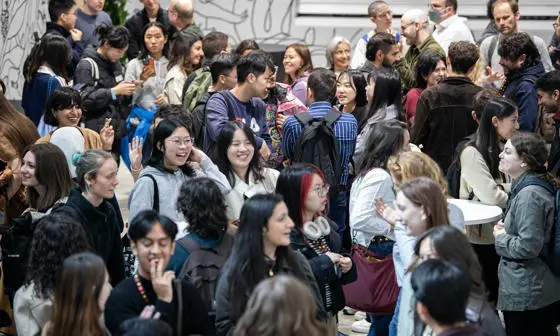 A group of students and staff stand in a room and talk