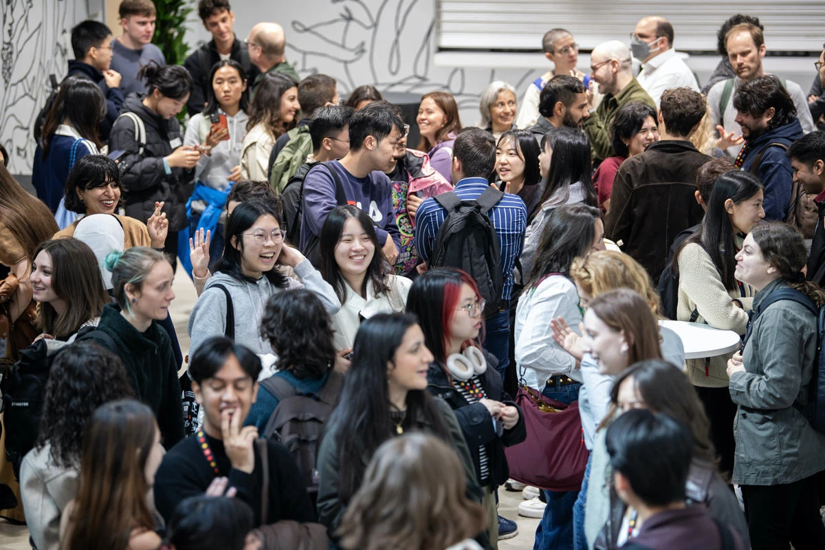 A group of students and staff stand in a room and talk