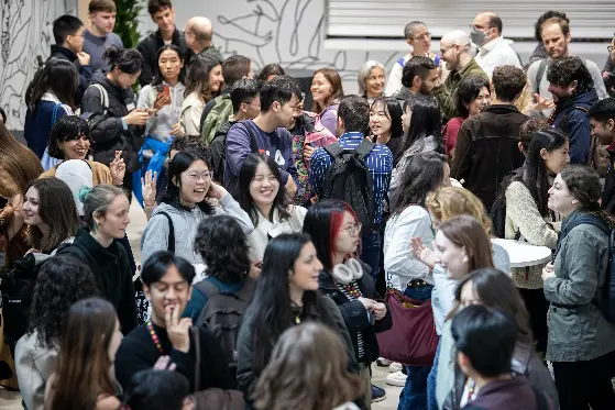 A group of students and staff stand in a room and talk